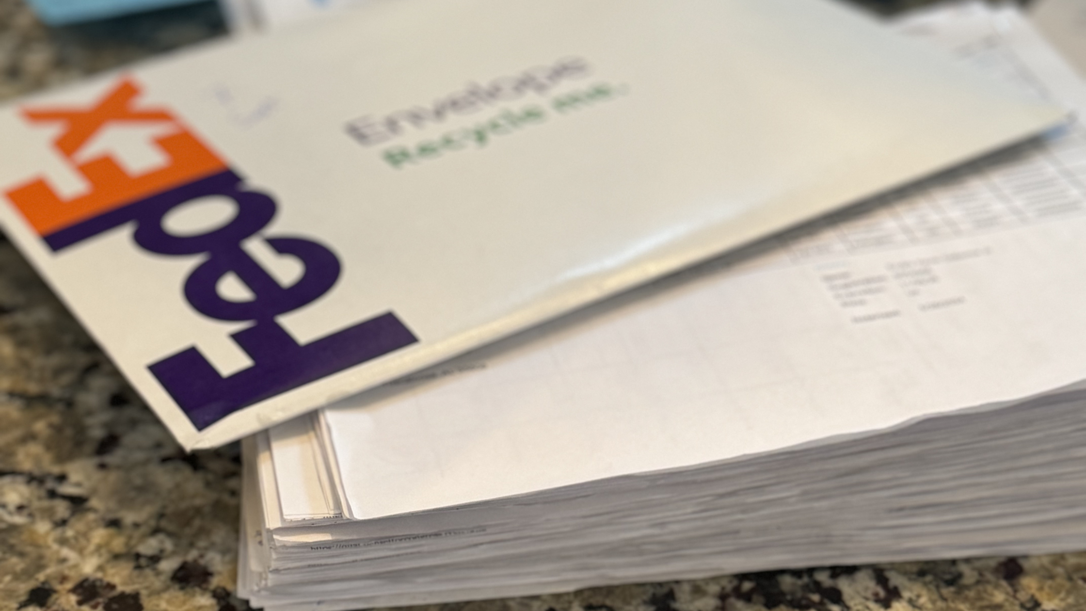 FedEx envelope on top of a stack of paper